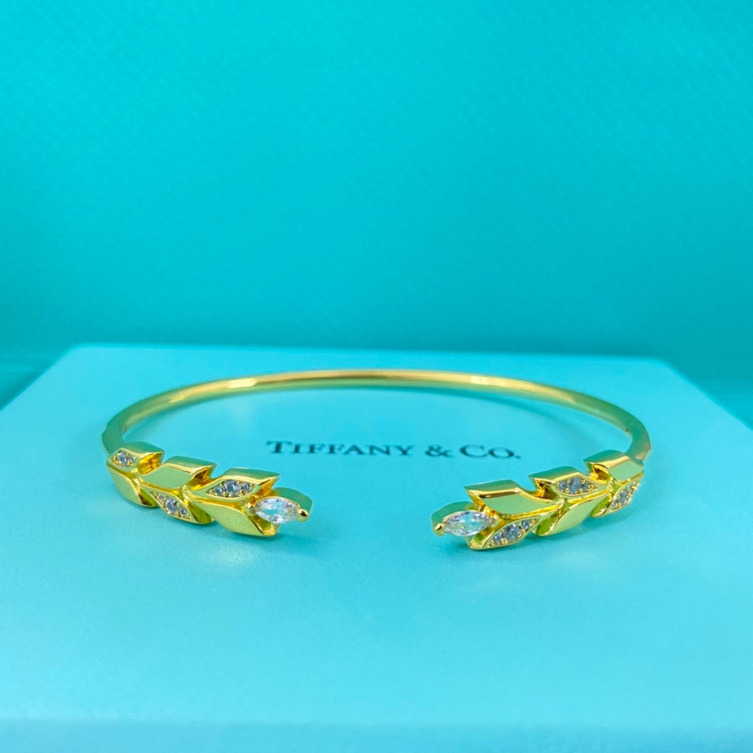 Gold-tone open leaf bangle with diamond-encrusted leaf accents