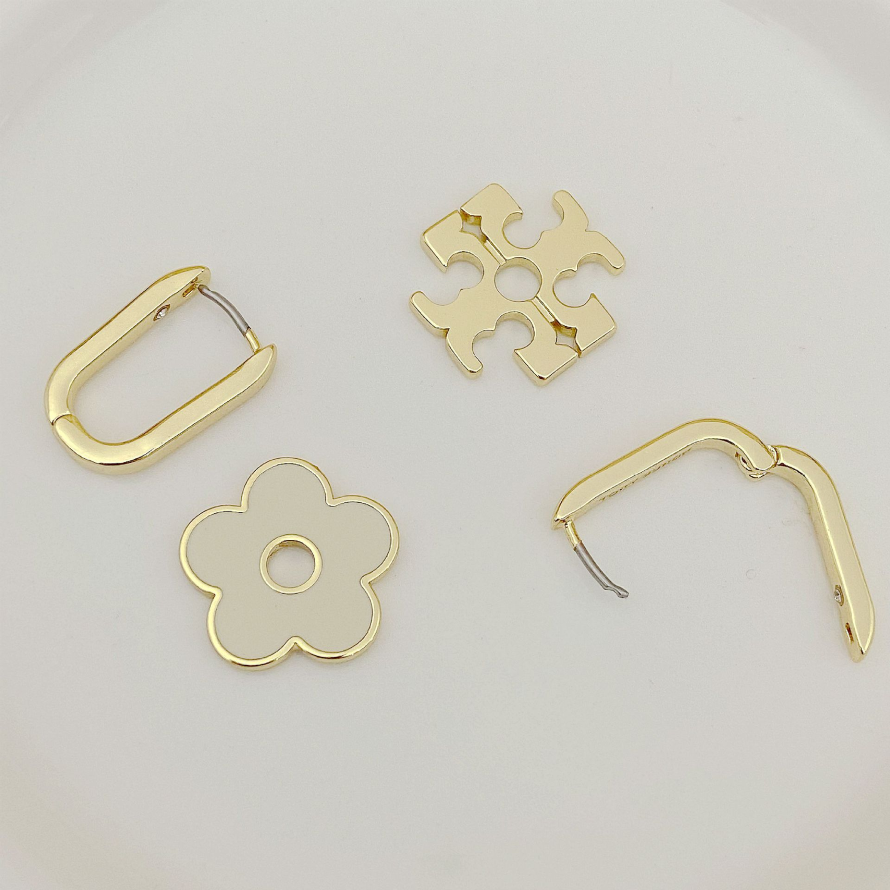 Tory Burch gold-tone metal earring set showing hinged backs and floral cutout fronts
