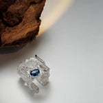 Silver-tone hollow lava ring with blue gemstone centerpiece, textured openwork