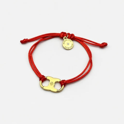 Woven enamel bracelet with red braided cord, gold logo charm, and round engraved tag.