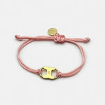 Woven enamel bracelet with pink braided cord and gold logo charm with enamel center.