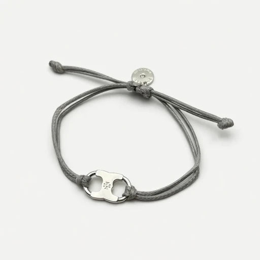 Woven enamel bracelet with gray braided cord and silver logo charm with enamel center.
