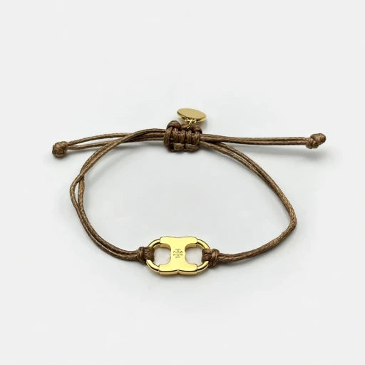 Woven enamel bracelet with brown braided cord and gold logo charm with enamel center.