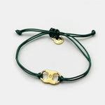 Adjustable drawstring bracelet with gold enamel toggle charm on dark green cords