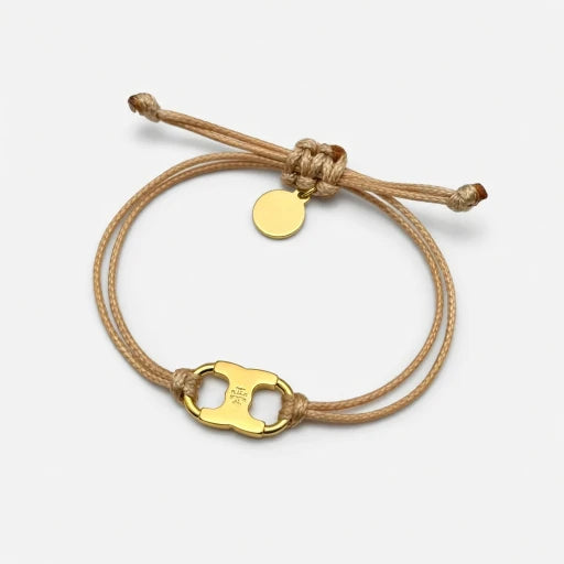 Adjustable drawstring bracelet with gold enamel toggle charm on tan cords