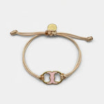 Adjustable drawstring bracelet with pink enamel toggle charm on beige cords