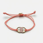 Adjustable drawstring bracelet with pink enamel toggle charm on coral double cords