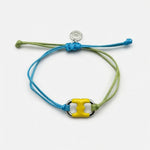 Adjustable drawstring bracelet with yellow enamel toggle charm on blue and green cords