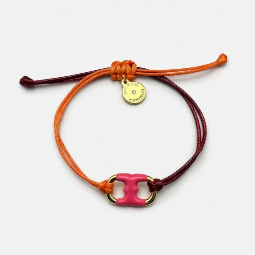 Adjustable drawstring bracelet with pink enamel toggle charm on orange and burgundy cords