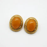 Pair of gold-tone oval stud earrings with glossy yellow glass cabochon and textured rim