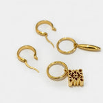 Gold metal hoop earrings with asymmetrical bullet drop and square filigree charm
