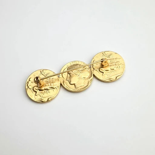 Matte gold coin brooch with three round engraved discs connected by a pin