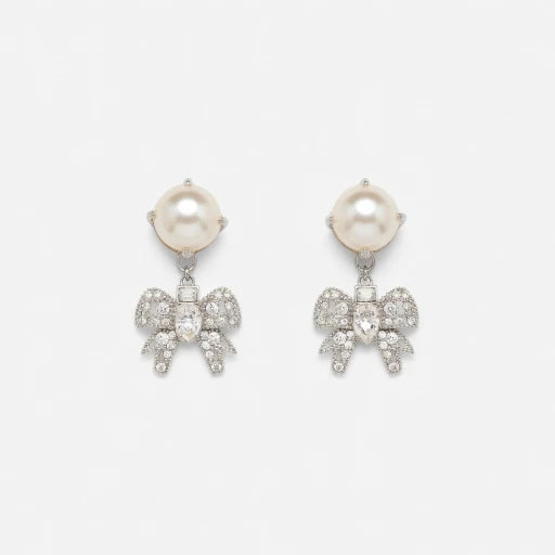 Silver-tone pearl drop earrings with crystal bow and small sparkle dangling details.
