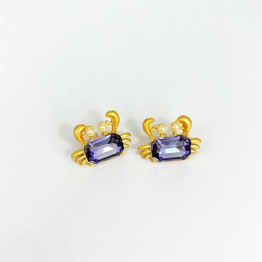 Crab-shaped crystal stud earrings with gold-tone settings, pearls, and a purple gem