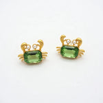 Crab-shaped crystal stud earrings with gold-tone settings, pearls, and a green gem