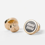 Gold-plated round enamel stud earrings with dark center and white 'miu miu' logo.