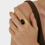 Gold-tone open ring with black oval stone, worn on finger