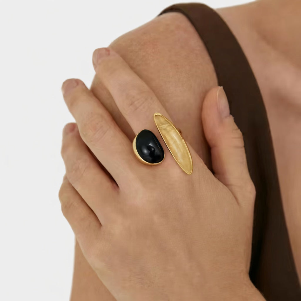 Gold-tone open ring with black oval stone, worn on finger