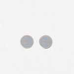 Silver-tone round enamel stud earrings with light gray 'miu miu' logo center.