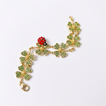 Gold-tone bracelet with green enamel four-leaf clover charms and red ladybug detail