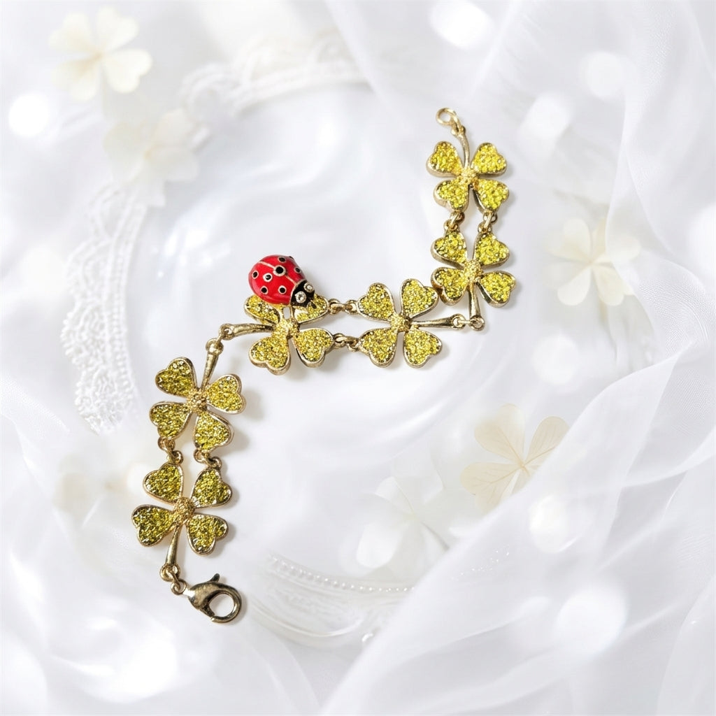 Gold-tone bracelet with gold glitter clover charms and red ladybug detail, toggle clasp