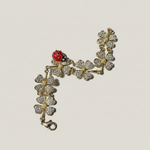 Gold-tone bracelet with rhinestone clover charms and red ladybug detail, lobster clasp