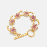 Gold-tone charm bracelet with pink flower pavé links and bar clasp