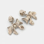 Silver metal bow earrings with clear backs and layered bow charms on clip posts