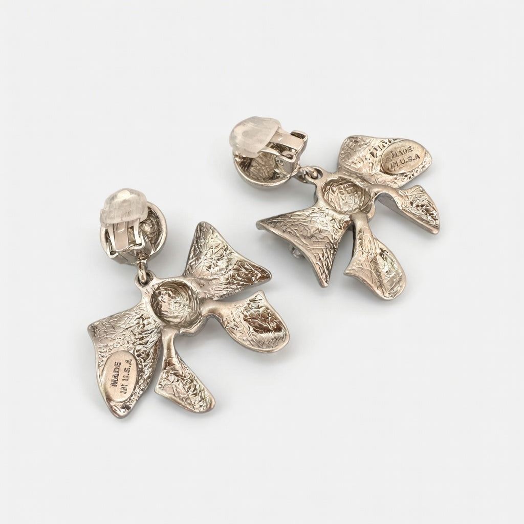 Silver metal bow earrings with clear backs and layered bow charms on clip posts