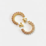 Gold-tone cubic zirconia hoop earrings with purple stones, hinged C-hoop style.