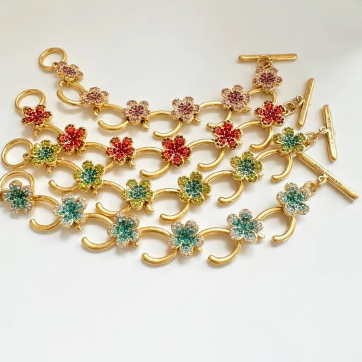 Gold-tone charm bracelet with mixed-color flower pavé links and bar clasp