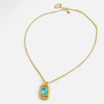 Gold square pendant necklace with hammered texture and blue faceted gemstone