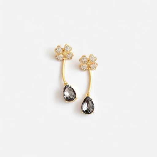 Four-leaf clover teardrop crystal drop earrings with dark gray stones and gold tone hooks.