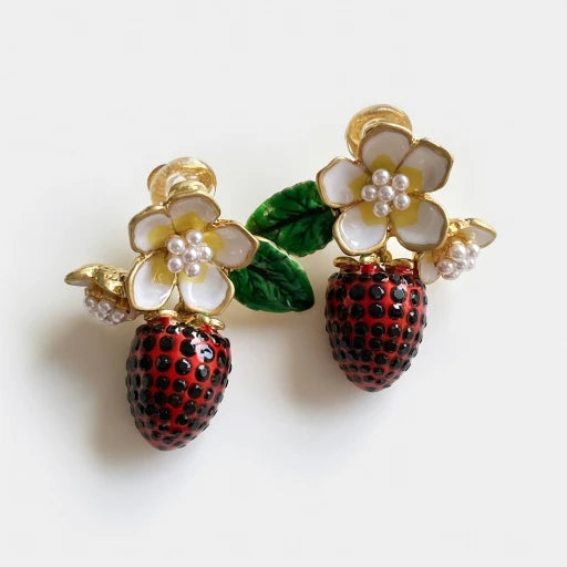 Gold-tone clip-on strawberry pendant earrings with enamel flower tops and pearl-like bead accents.