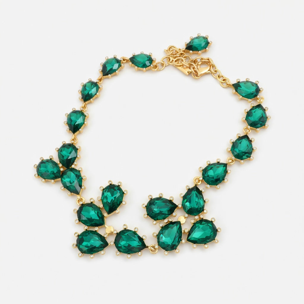 Gold teardrop crystal necklace with teal green stones and linked cluster design.