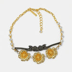 Gold-tone pendant necklace with red enamel flower charms, black center bar and crystals