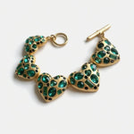 Gold-tone heart bracelet with green gemstone heart links and ring clasp