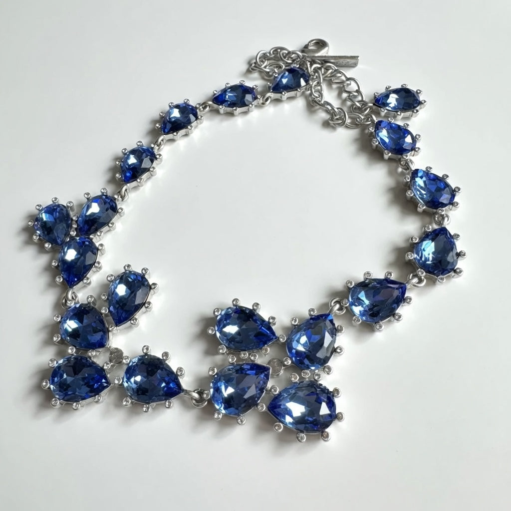Silver teardrop crystal necklace with blue stones and linked floral clusters.