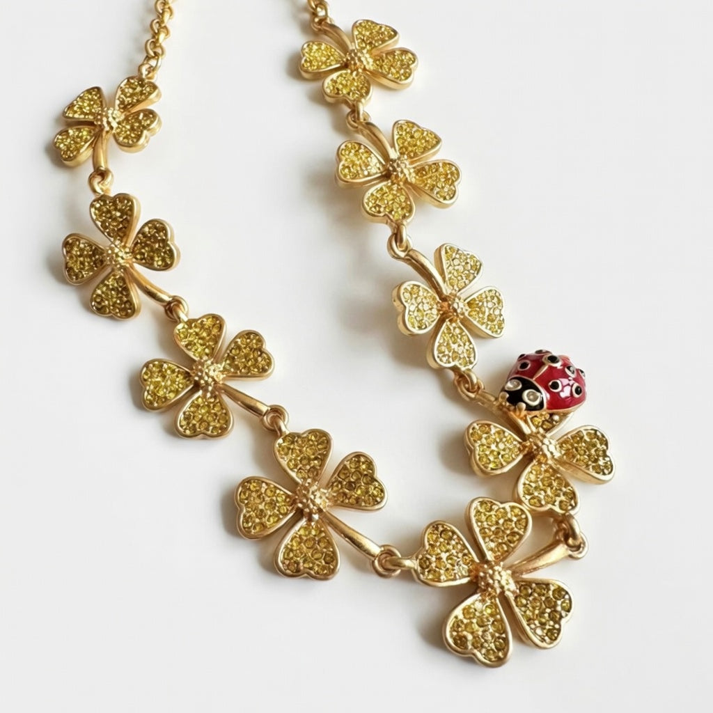 Clover crystal necklace with red ladybug charm, gold-tone links, close-up