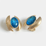 Oval crystal earrings with gold-tone curved settings and bright blue oval stones