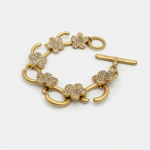 Gold-tone charm bracelet with white flower pavé links and bar clasp