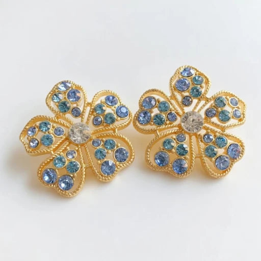 Floral stud earrings with blue pavé petals and round clear center, gold-tone setting.