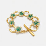 Gold-tone charm bracelet with green flower pavé links and bar clasp