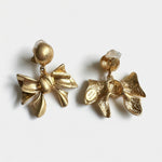Gold metal bow earrings with round stud tops and layered bow charms, textured finish