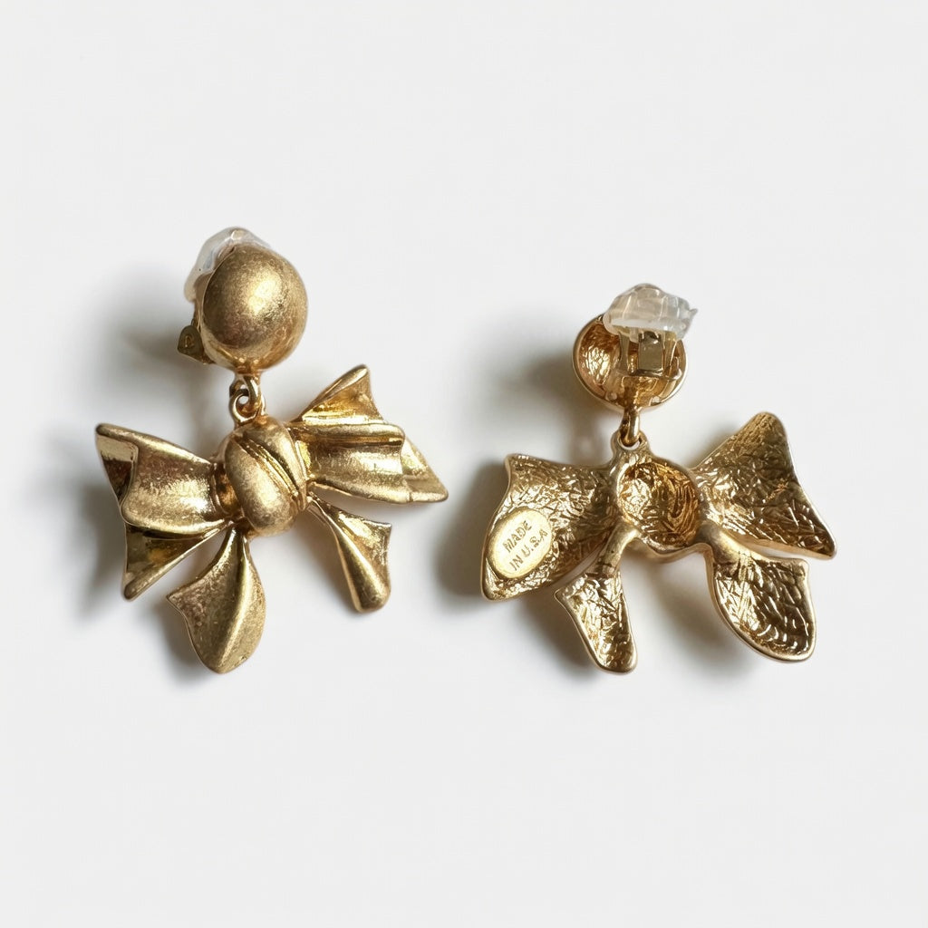 Gold metal bow earrings with round stud tops and layered bow charms, textured finish
