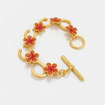 Gold-tone charm bracelet with red flower pavé links and bar clasp