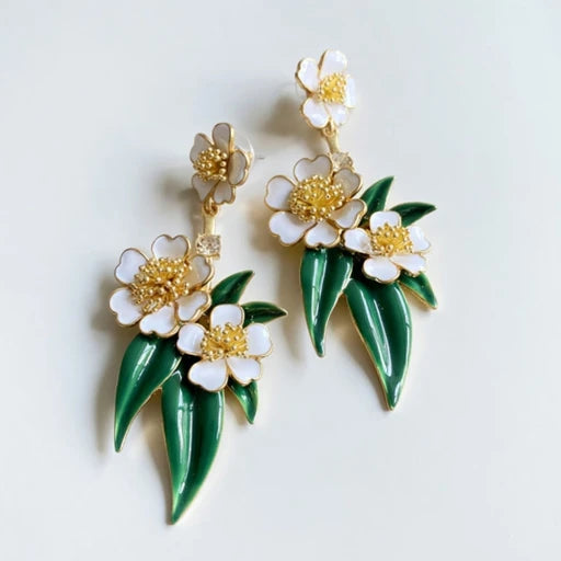 Enamel floral drop earrings with white flowers, gold centers, and green enamel drops