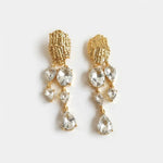 Asymmetrical crystal tassel earrings with white teardrop stones and gold-tone drops