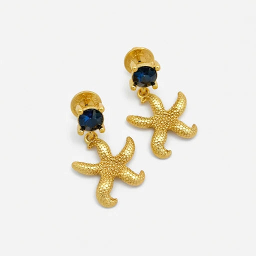 Gold starfish stud earrings with dark blue jeweled centers on white