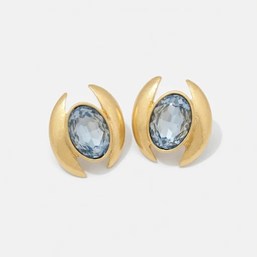Oval crystal stud earrings with light blue faceted stones and gold-tone curved crescent bezels